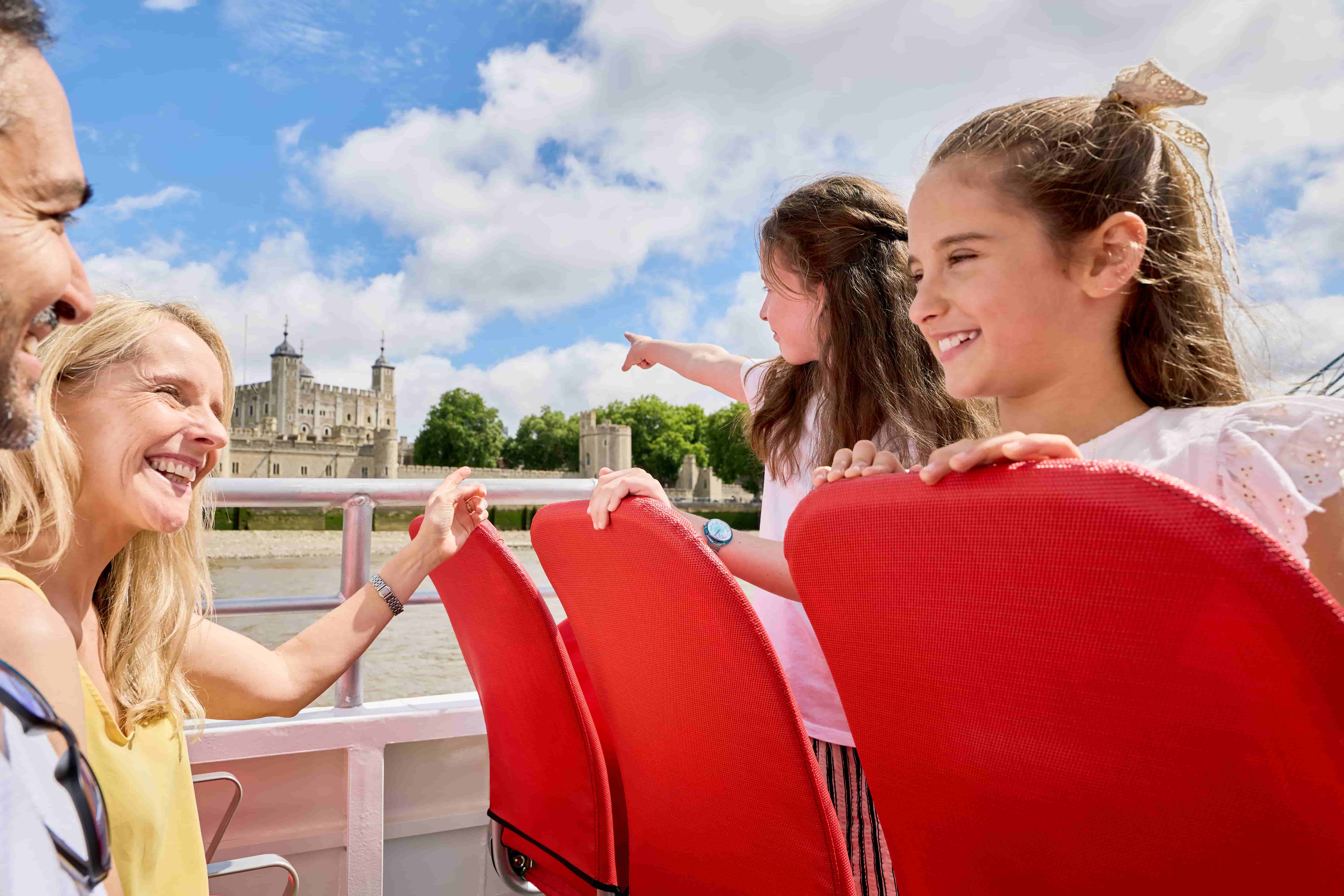Family sightseeing cruise passing the iconic Tower of London on a River Thames tour.